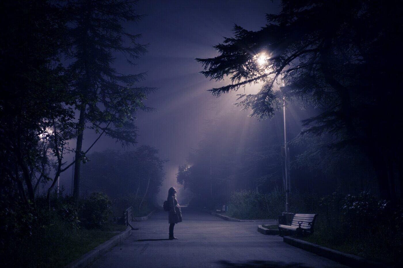 Saving Energy And Money With Solar Led Street Lights 4 Woman looking up at streetlight in foggy park - saving money and energy with solar led streetlights