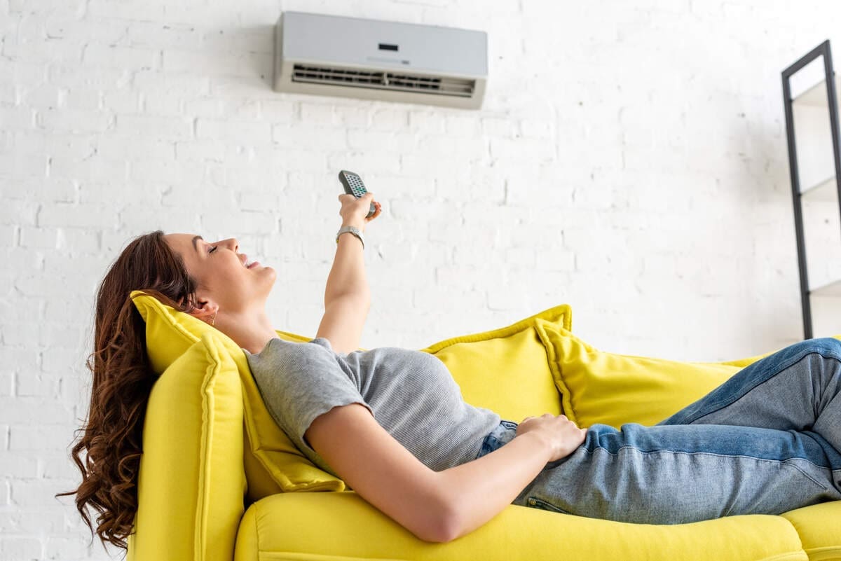6 Tips To Avoid Costly Ac Repairs 2 Woman lying down in front of air conditioner keeping cool
