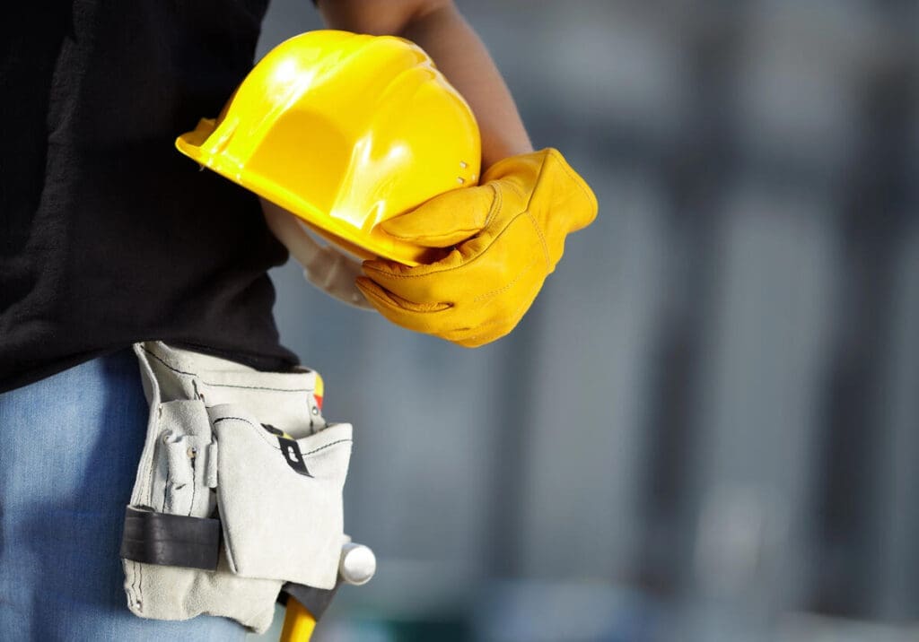 Construction worker holding hard hat with gloves