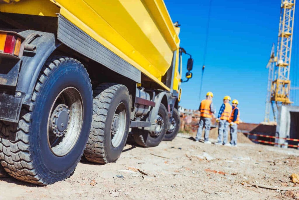 Dump truck on construction site with construction workers in background